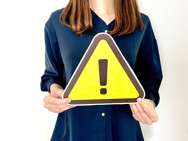 注意マークのアイコンを持った女性